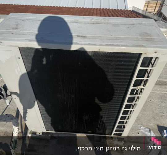 יחידת מיזוג אוויר על גג עם צל של אדם